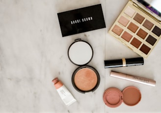 photo of assorted makeup products on gray surface