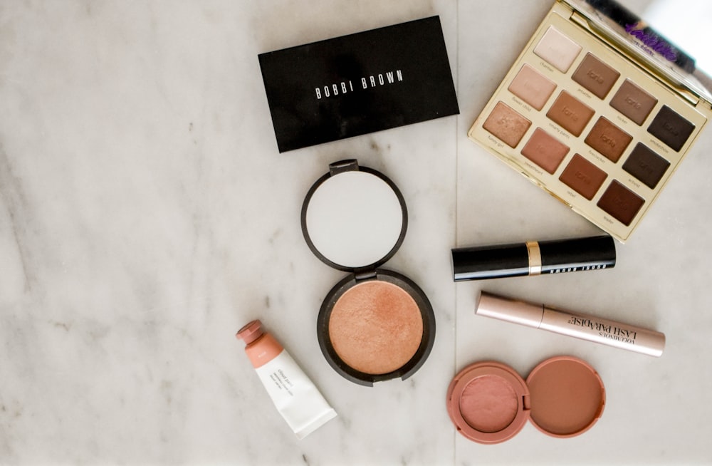 photo of assorted makeup products on gray surface