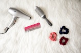 gray corded hair dryer and red comb