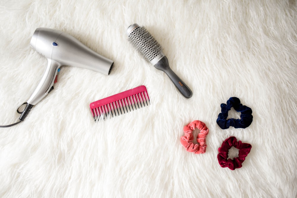 gray corded hair dryer and red comb