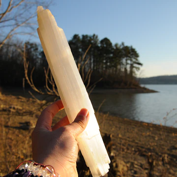 Hands holding crystals with a backdrop of a sunrise over a misty forest.