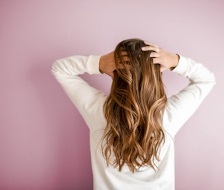 woman in white long-sleeved shirt standing in front of pink wall