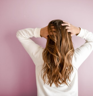 woman in white long-sleeved shirt standing in front of pink wall