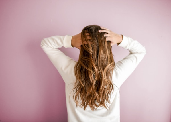 woman in white long-sleeved shirt standing in front of pink wall