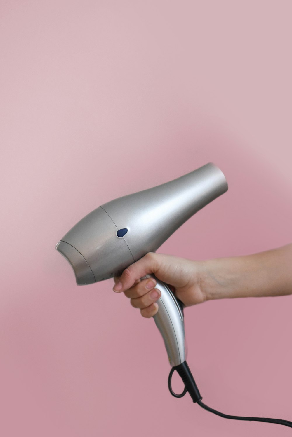 person holding gray corded hair dryer