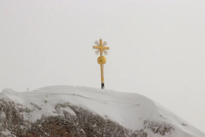 A golden cross silhouetted against a sunrise over a quiet mountain path.