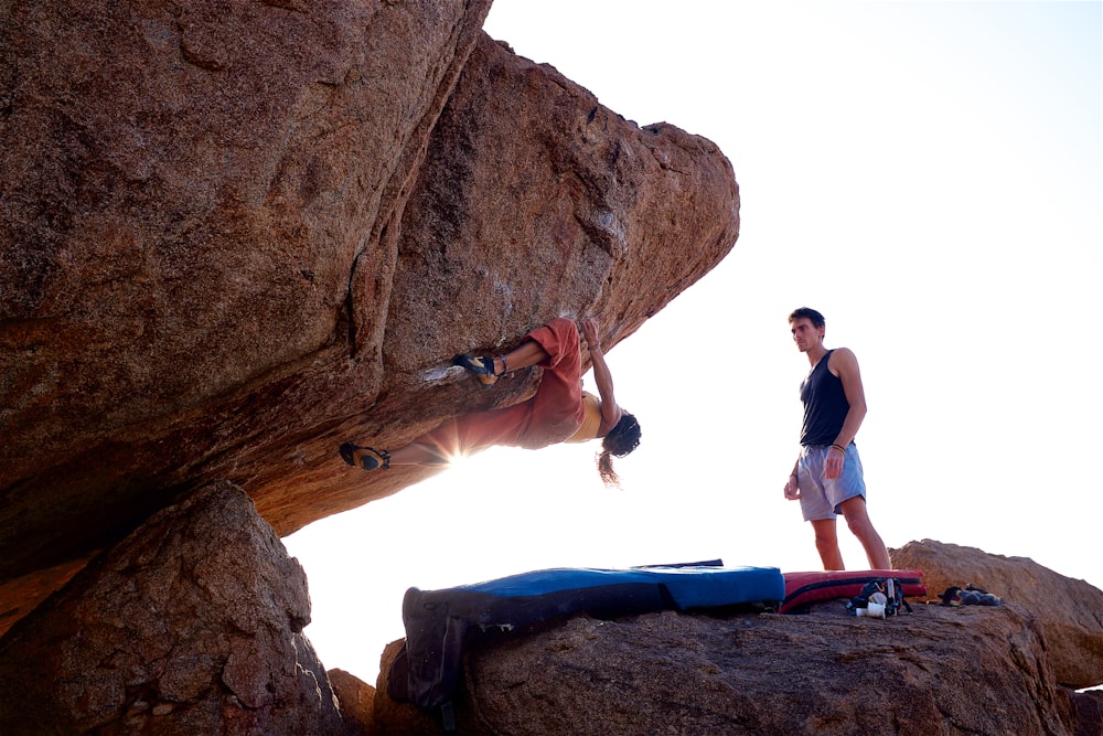 Un hombre parado en la cima de una roca junto a otro hombre