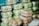 Several stacks of clear plastic containers filled with food items, with some of the containers holding light green items and others holding brown baked goods.