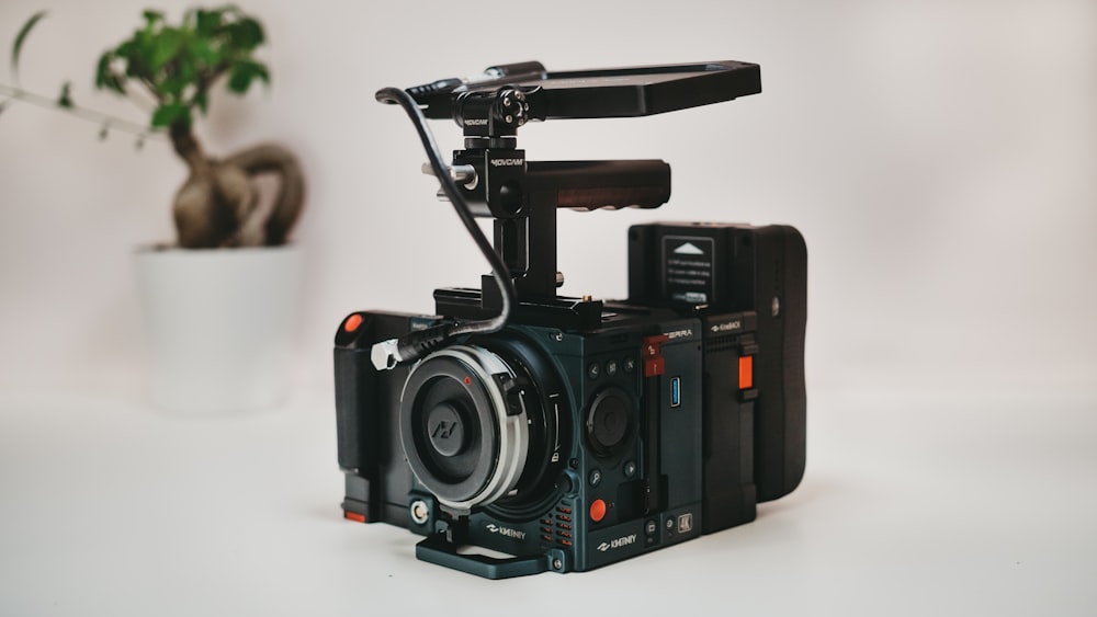 a small camera sitting on top of a table next to a potted plant