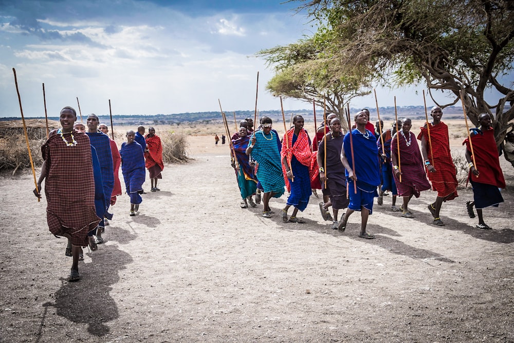 group of people walking in line holding sticks