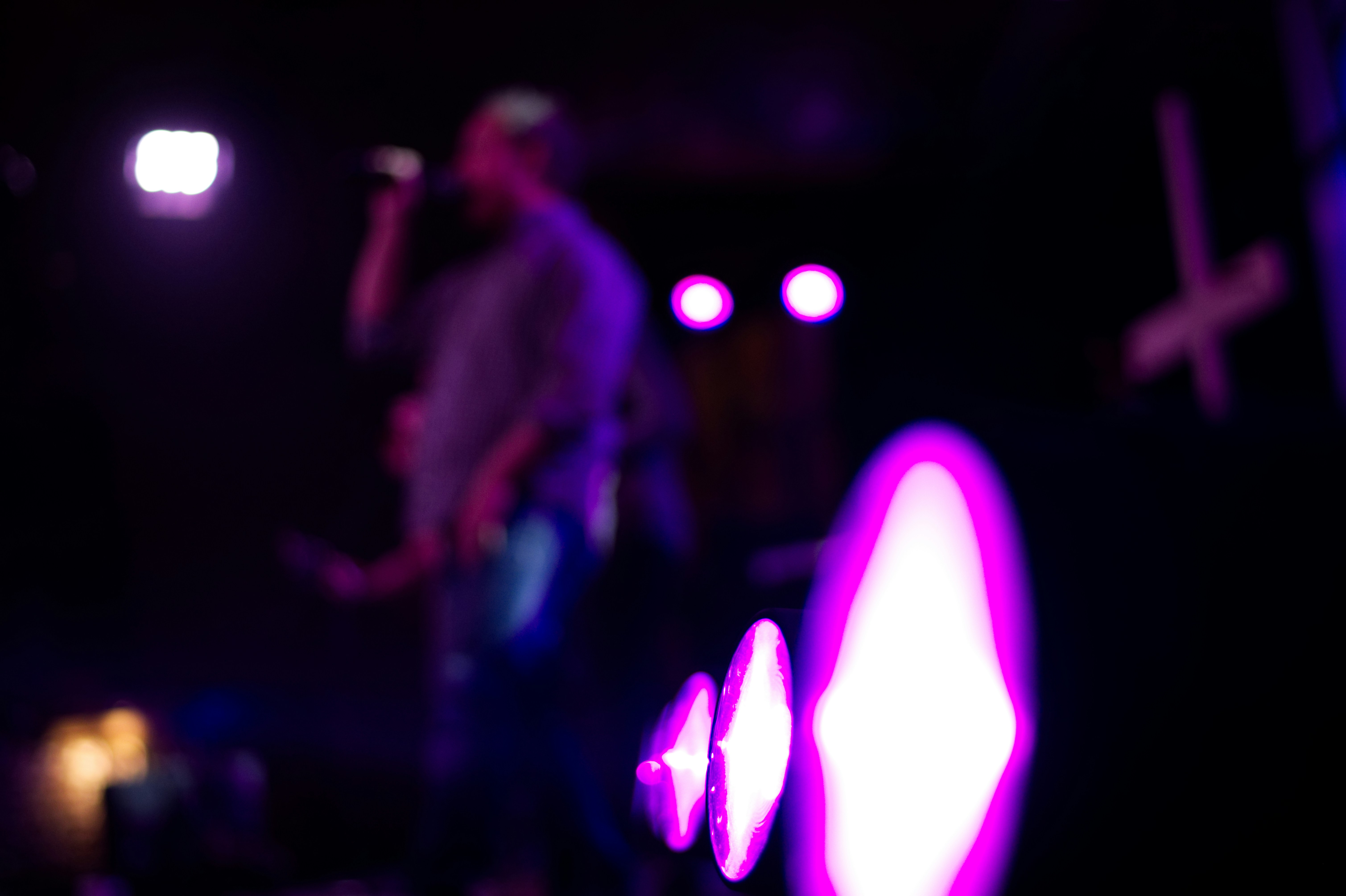 Singer performing on stage with pink and purple neon lights in background