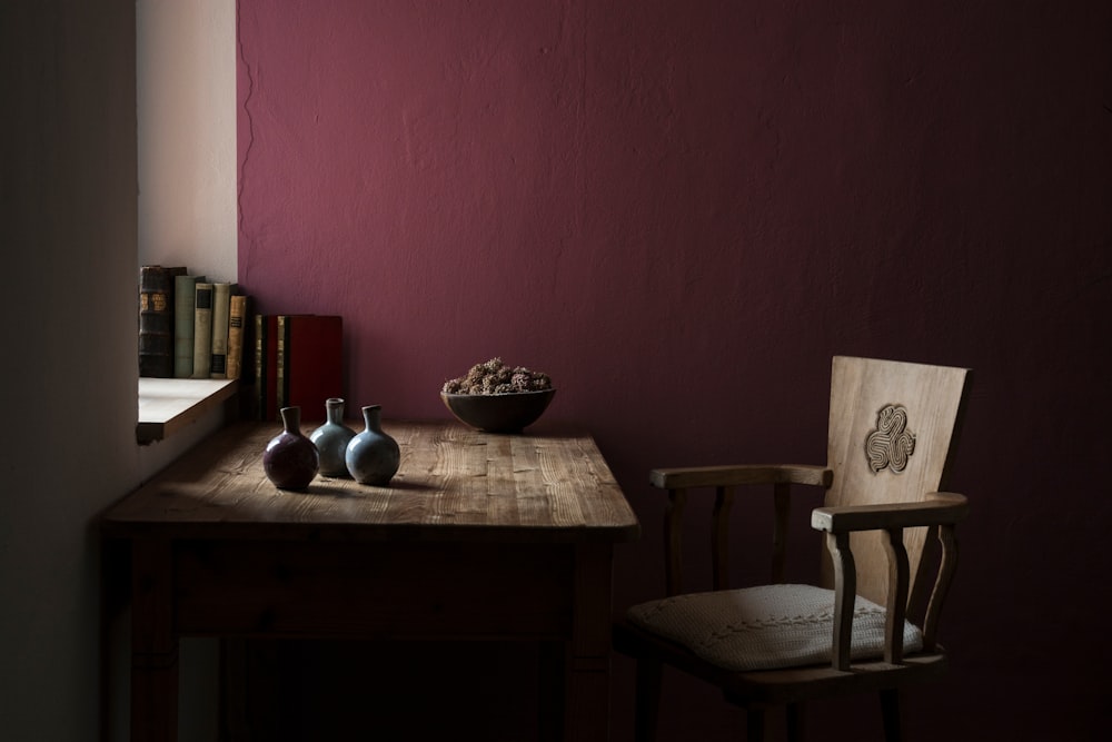 three vases on table beside chair inside maroon painted room