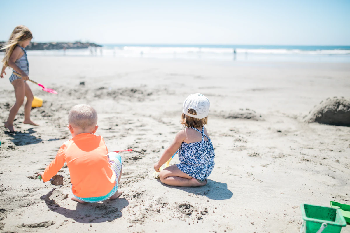 Trois enfants qui jouent dans le sable à la plage