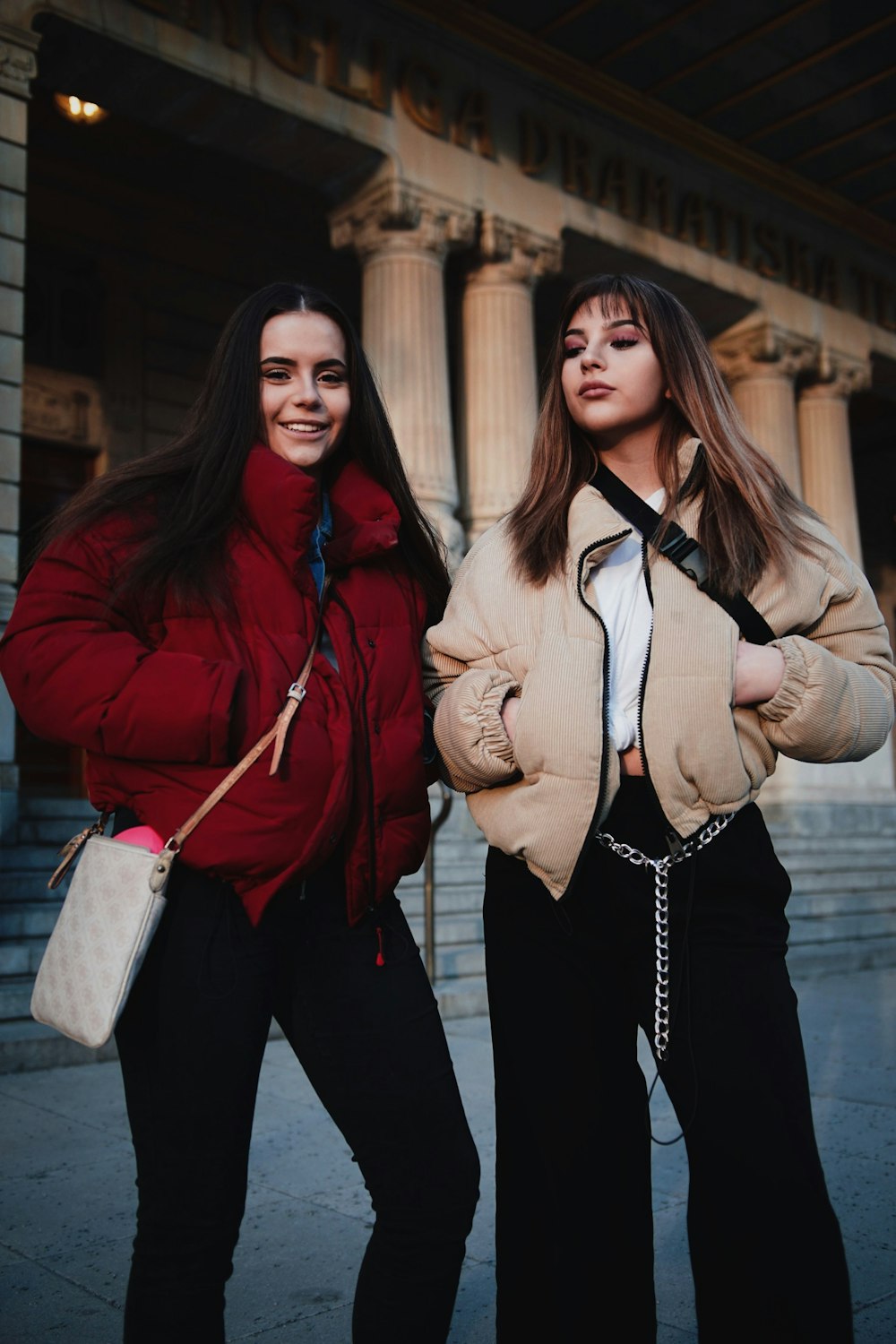 two woman standing near building