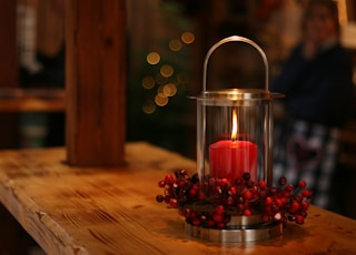 red lighted candle on brown wooden frame
