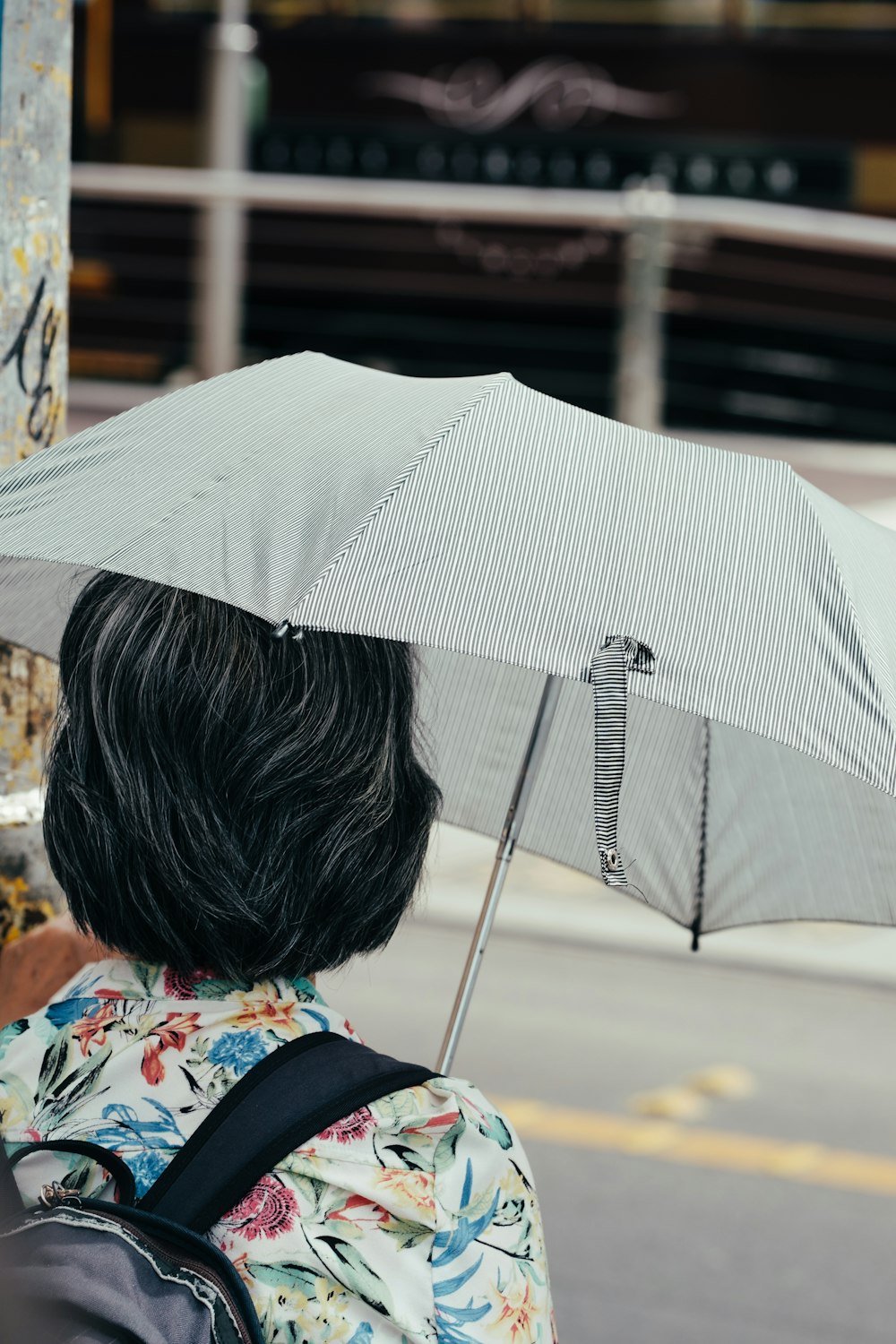 Mujer bajo paraguas gris cerca de la carretera