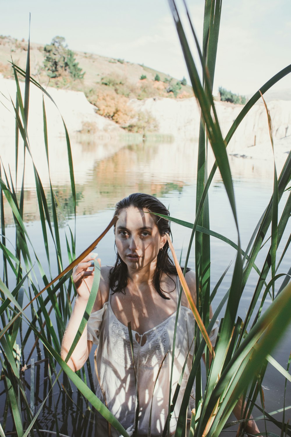 Mujer de pie en el lago rodeada de plantas de hojas verdes