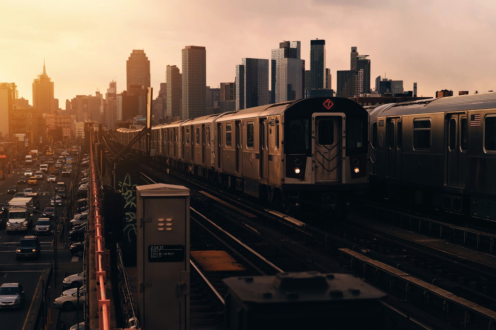 Elevated 7 subway train in Queens at sunset with the Manhattan skyline behind it