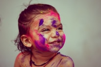 A joyful child with a painted face smiling brightly.