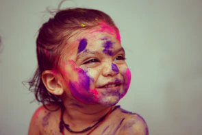 A joyful child smiling while coloring a bright, faith-themed page with crayons.