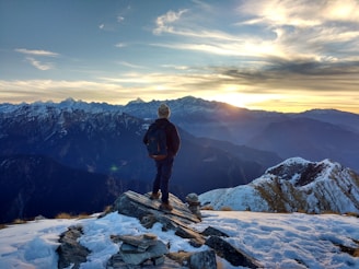 A traveler with a backpack admiring mountain landscapes at sunrise.