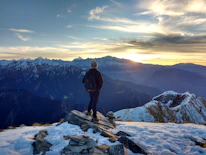 A traveler with a backpack looking over a scenic mountain vista at sunrise.