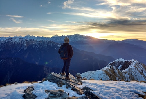 person standing on top of the mountain facing sunrise