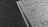A close-up view of an open notebook with graph paper containing handwritten mathematical notes and equations. The notebook rests on a wooden surface with a focus on the neatly aligned lines and clear, precise writing. The overall scene is presented in black and white, giving a classic and studious appearance.