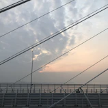 Engineers inspecting the cables of a suspension bridge at sunset.