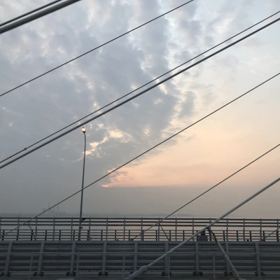 Engineers inspecting the cables of a suspension bridge at sunset.