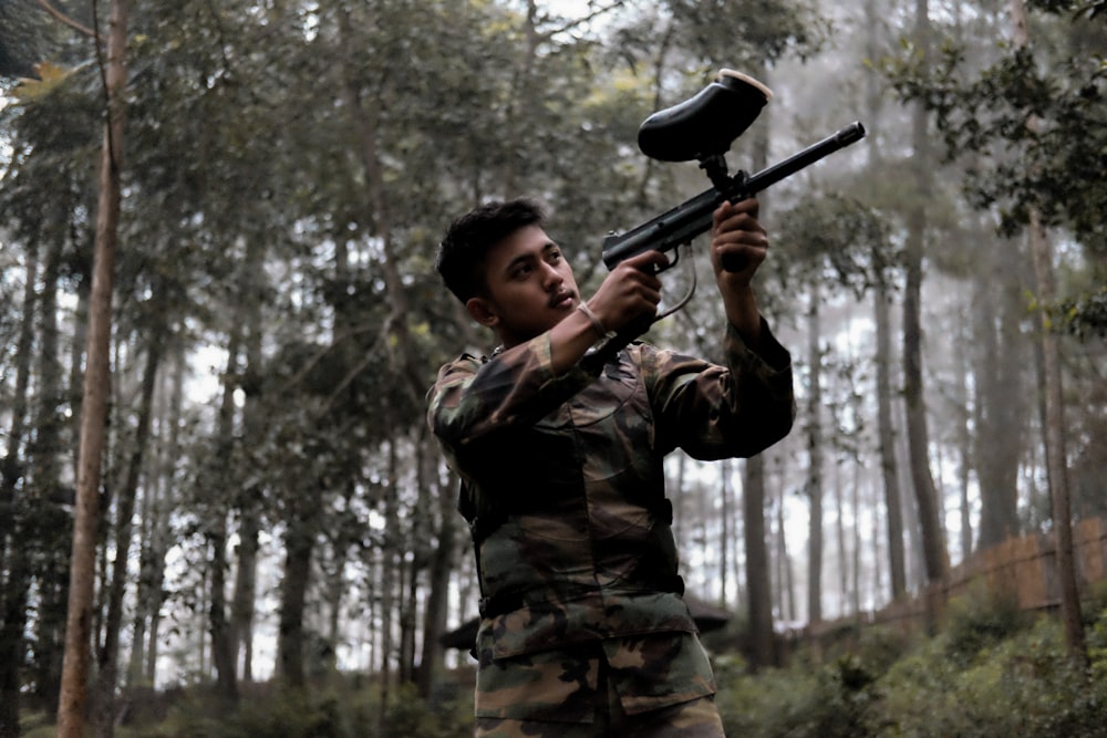 숲에 페인트볼 총을 들고 있는 군인