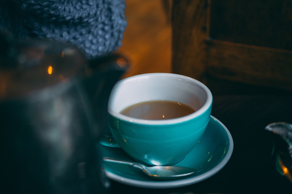 teal and white ceramic cup half-filled with coffee