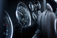 A close-up view of a vehicle dashboard featuring various gauges including a speedometer, odometer, and other dials. The design is classic with chrome edges and a focus on the speedometer in the center.