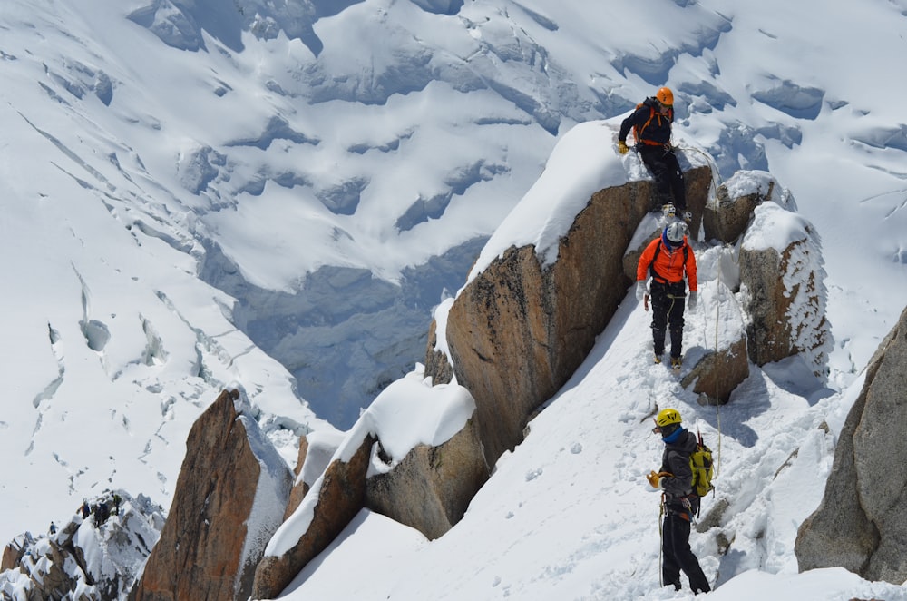 three person trekking on snow field mountain at daytime