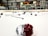 An indoor ice hockey rink with various pieces of hockey equipment scattered on the ice, including helmets and sticks. Banners and flags adorn the walls above the rink, and a scoreboard displays the end of a game.