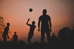 A group of smiling friends mid-passing the ball in a sunny park, embodying the spirit of tiki-taka.