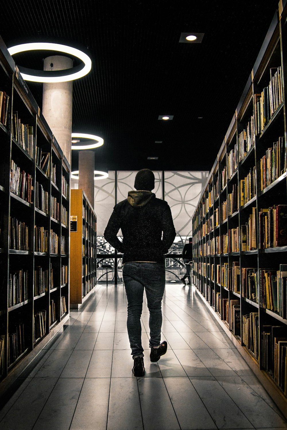 man walking between bookshelf