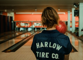 person holding bowling ball facing bowling pins