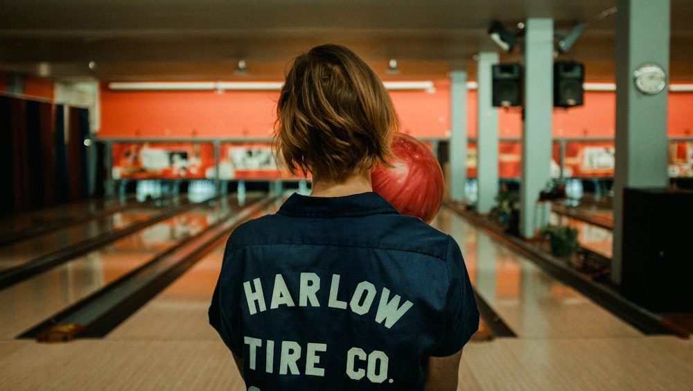 person holding bowling ball facing bowling pins