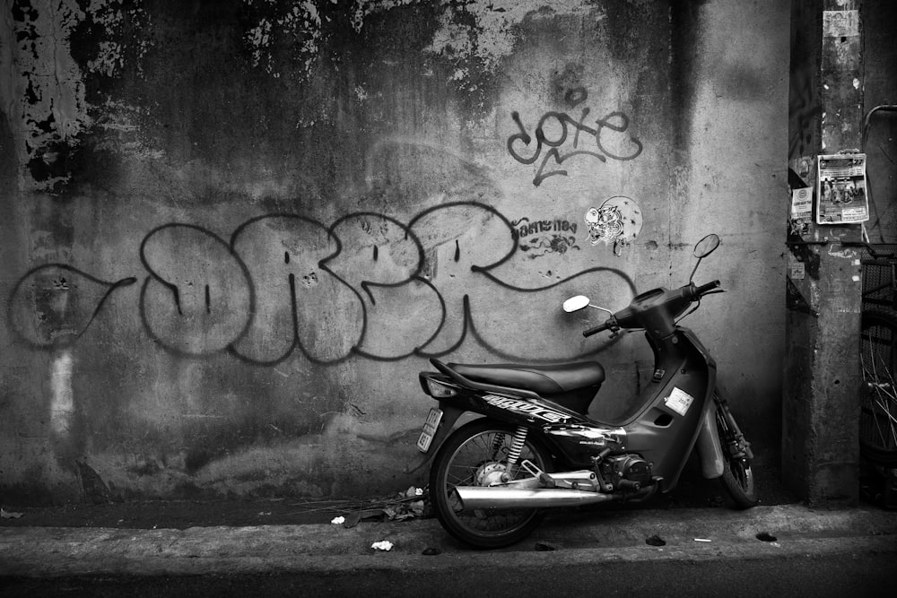 motorcycle park near wall grayscale photography
