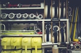 A neatly organized collection of firefighting equipment, including coiled hoses, metal nozzles, yellow plastic containers, and various metal pipes and fittings. The equipment is stored within compartments on a fire truck, showcasing its readiness and accessibility.