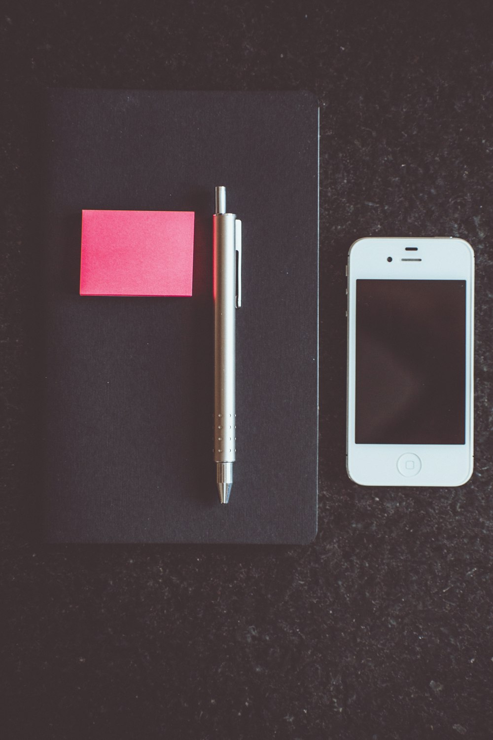 white iPhone 5 beside pen and book