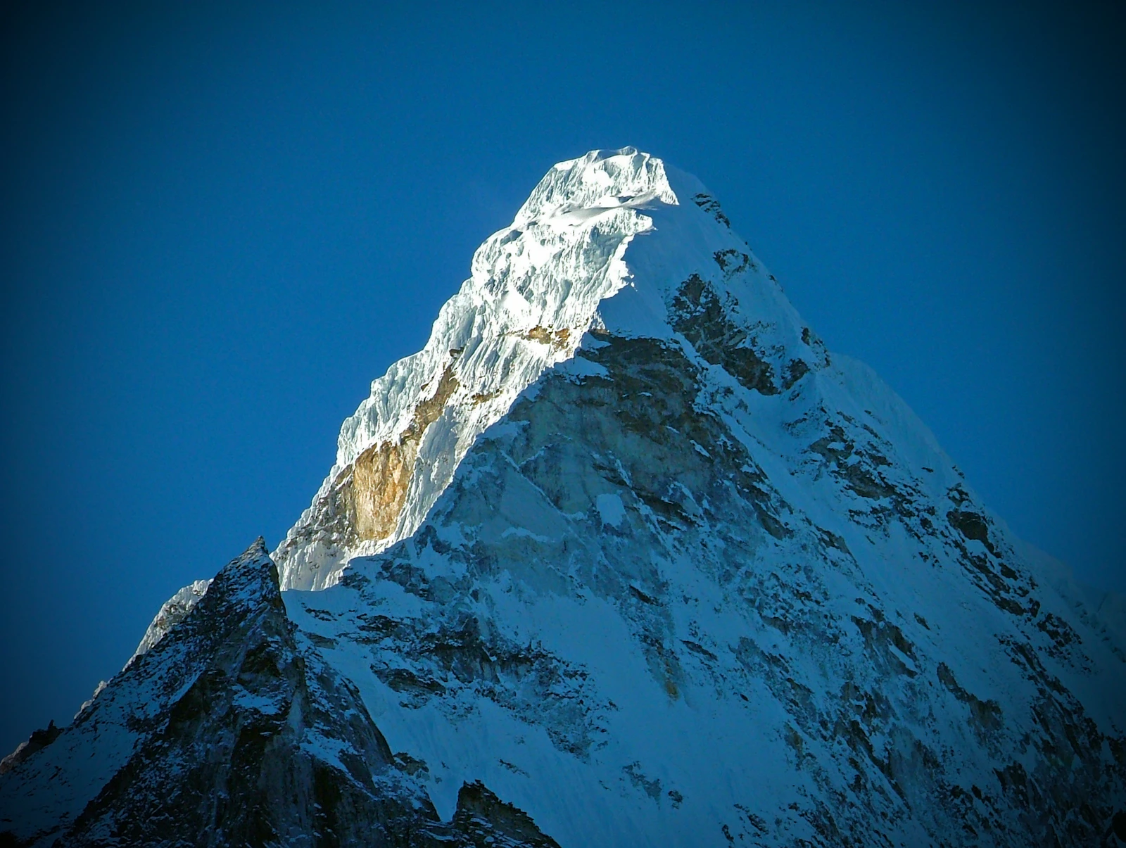 Snow-plumed summit ridge of Ama Dablam against deep blue sky, Khumbu, Nepal