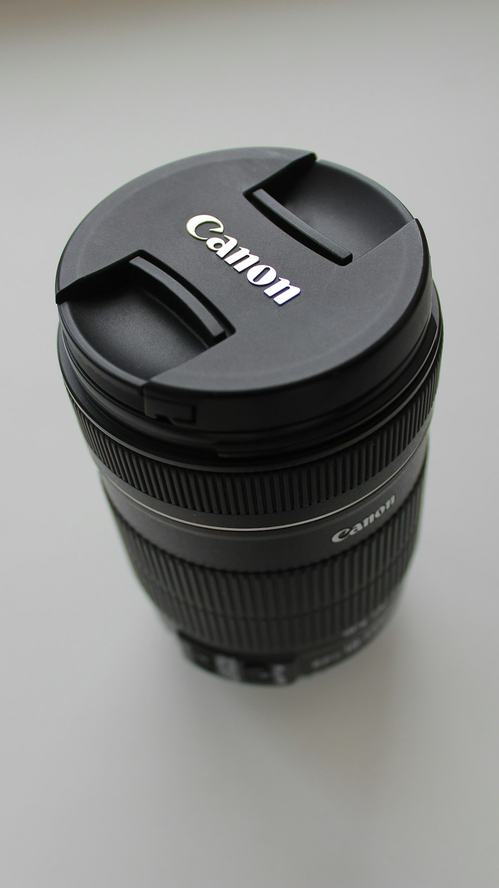 Lente de cámara Canon DSLR negra sobre mesa blanca