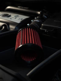 Red high-flow cone air filter mounted inline in an engine bay