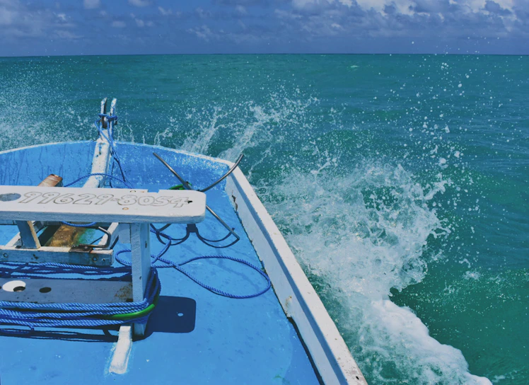 A vibrant boat cutting through crystal-clear waters near Ilhabela's coastline under a bright blue sky.