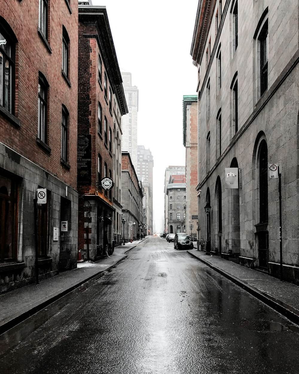 person standing beside car between buildings