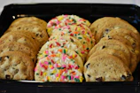 An assortment of golden millet cookies arranged neatly on a rustic wooden tray.