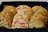 An assortment of cookies neatly arranged in a black tray, featuring chocolate chip cookies on both sides and a row of sugar cookies with colorful sprinkles in the center.