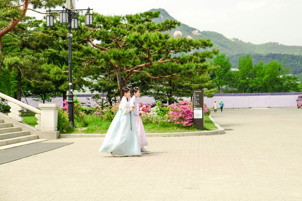 Mujer en vestido de novia blanco de pie cerca del árbol verde durante el día